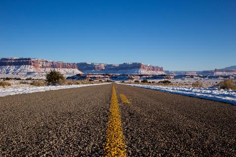 Empty road with snow capped mountains